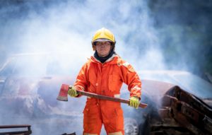 Firefighter man wearing protective fire suite and helmet with equipment and accessories is fire safety accident protection with white fire smoke background.