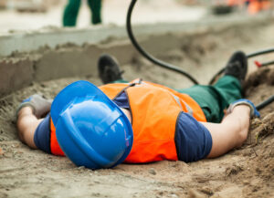 Injured worker laying flat in a field of dirt.